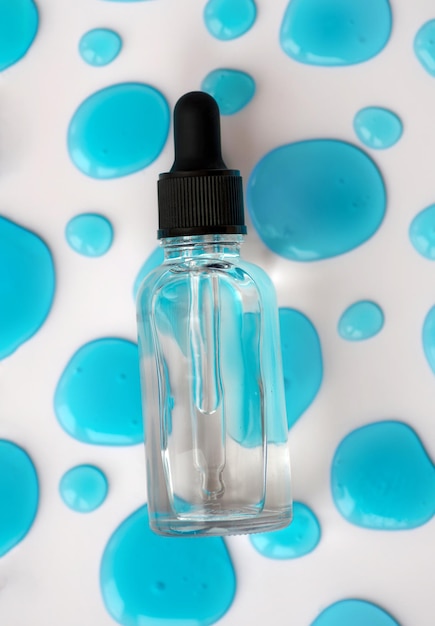 Foto bottiglia trasparente per gocciolini cosmetici su gel blu gocce per viso siero acido ialuronico olio essenziale