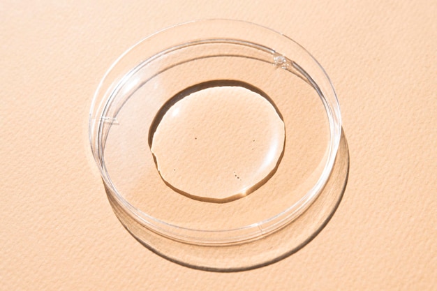 Transparent cosmetic texture in a glass container on a beige background top view