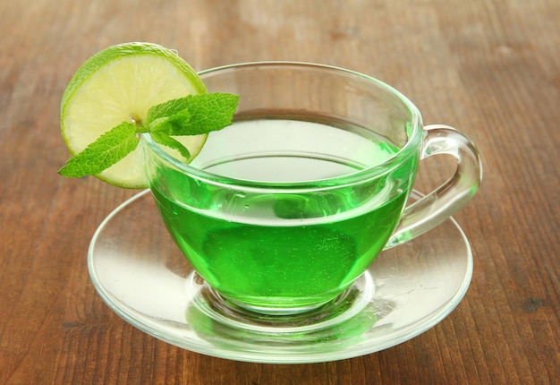 Foto tazza trasparente di tè verde con lime e menta su sfondo di legno