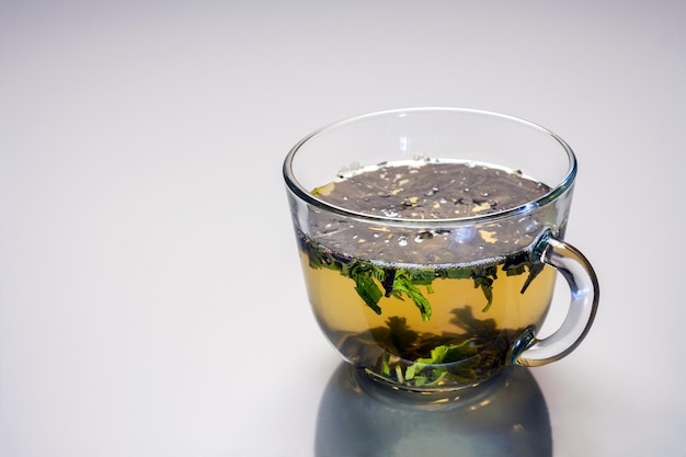 A transparent cup with green tea is reflected in the gray glass copy space