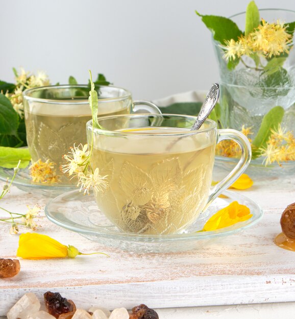 Transparent cup with tea from linden on white wood board