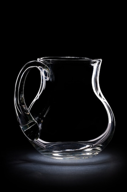 Transparent empty glass jug on black background