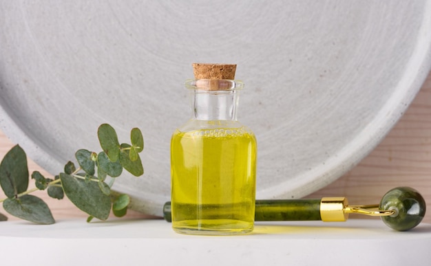 Transparent glass bottle with yellow oil and eucalyptus branch cosmetic product