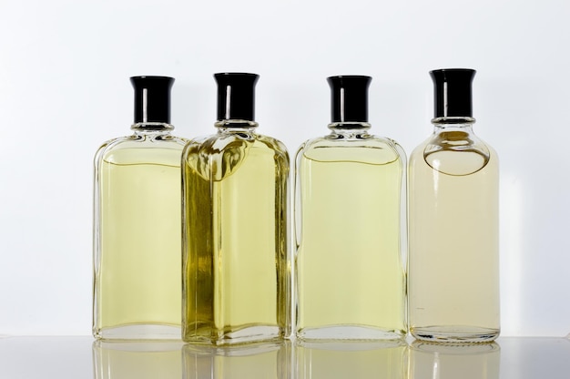 Transparent glass jars with perfume liquid stand on a white surface