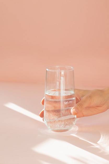 Transparent glass on a peach background in the sunlight gives beautiful rays and glare