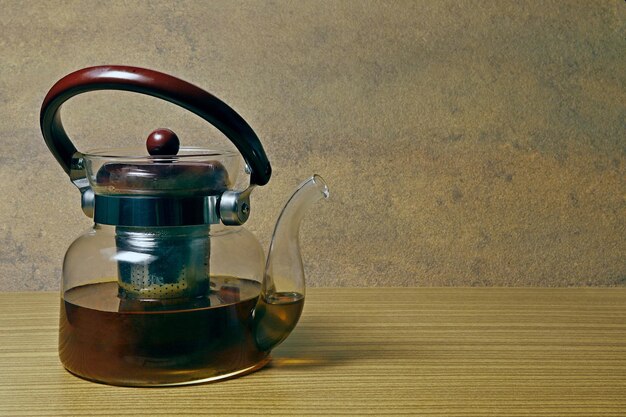 Transparent glass teapot half filled with tea