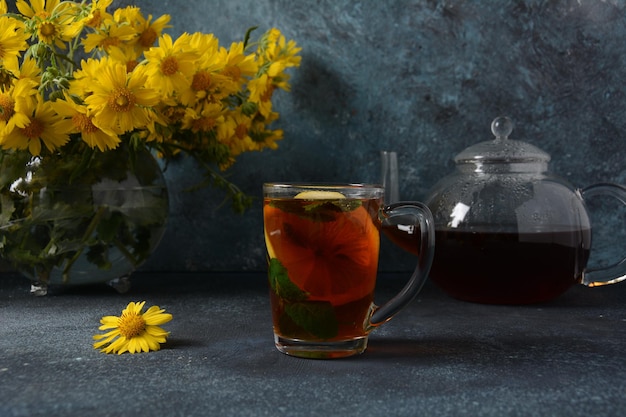 Transparent glass teapot with black tea and a glass mug with lemon mint and tea