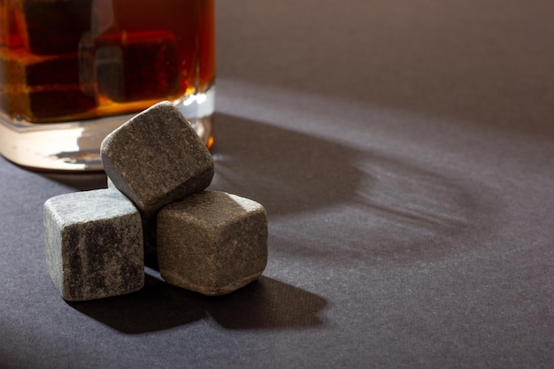 Transparent glass with whiskey on a dark background with bright rays of light Whiskey stones in a glass glass