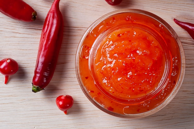 Transparent glasses of pepper jam on wooden table. Top view