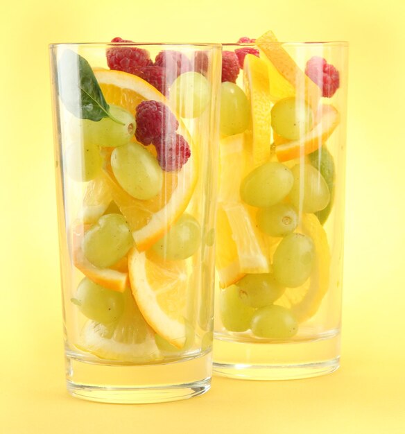 Фото Прозрачные стаканы с цитрусовыми фруктами на желтом фоне