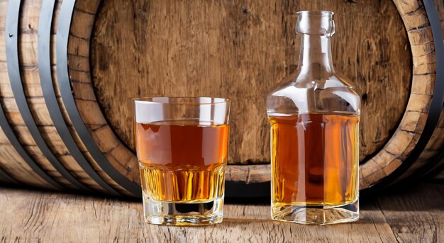 transparent glasses with whiskey with barrels on a wooden background