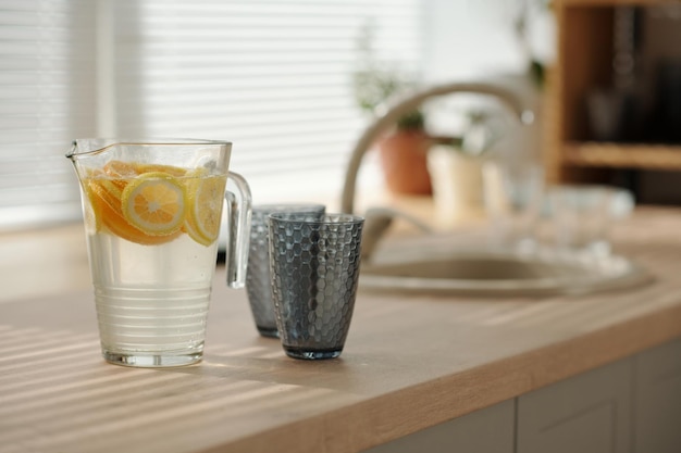 Transparent jug with cool refreshing homemade lemonade and two glasses