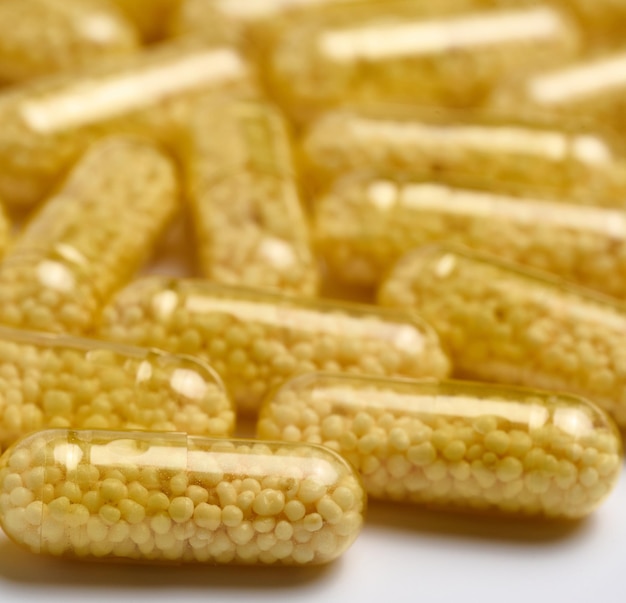 Transparent medical capsules with yellow granules inside on a white background tablets for treatment vitamins