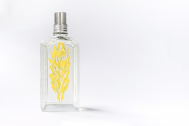 Transparent perfume bottle on white decorated with yellow flower petals