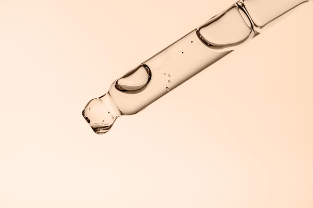 Transparent pipette with cosmetics on a beige background