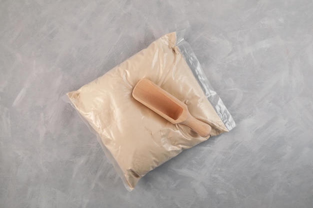 Transparent plastic bag of Soy Protein isolate and wooden scoop. Pure powder isolated from soybean.