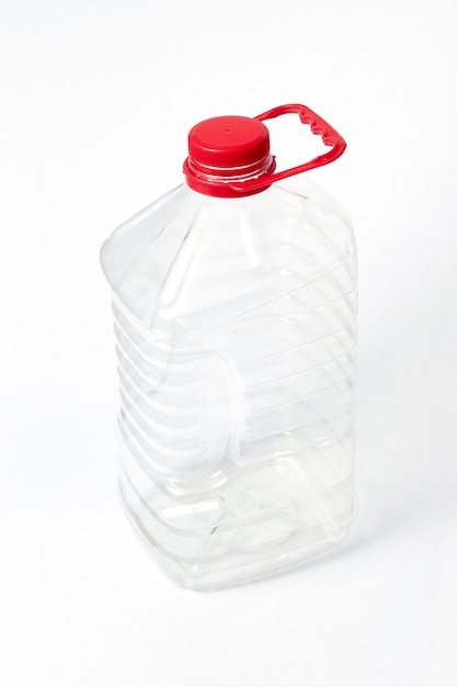 Transparent plastic big canister for water and other liquid with red cover on a light gray background with copy space.