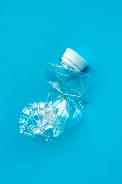 Фото Прозрачная пластиковая бутылка на сплошном синем фоне для переработки отходов концепция разделения отходовзащита окружающей среды переработка мусора сохранение природы селективный фокус