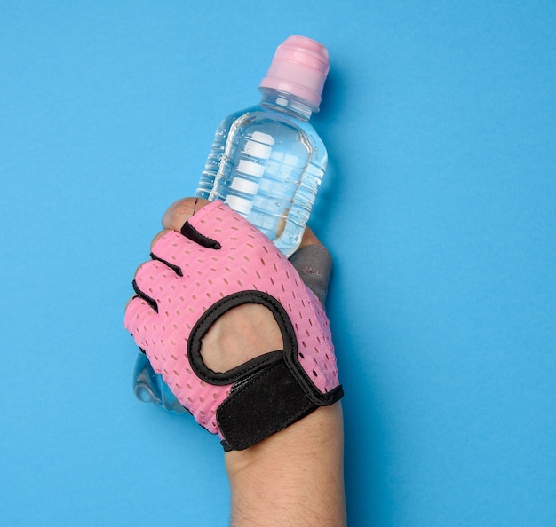 Фото Прозрачная пластиковая бутылка с пресной водой в женской руке на синем фоне
