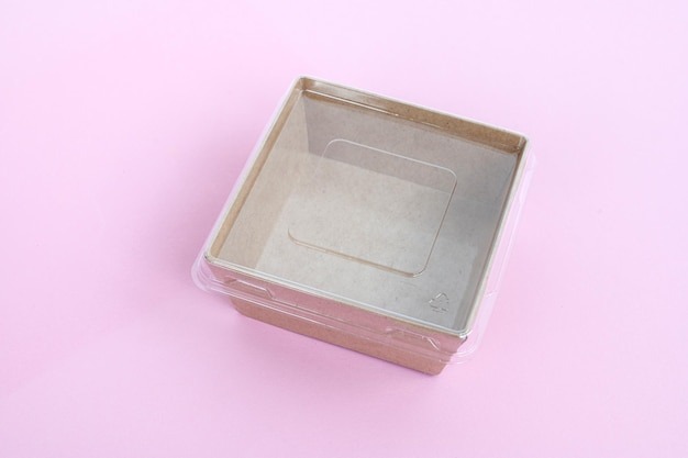 Прозрачный пластиковый и картонный контейнер для продуктов питания на розовом фоне