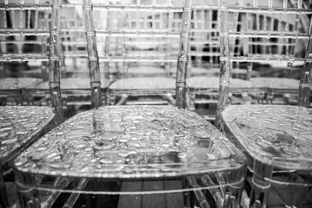 Transparent plastic chairs with rain drops on the surface, macro. Close-up - water drops on grey surface, use for web design and abstract background texture.