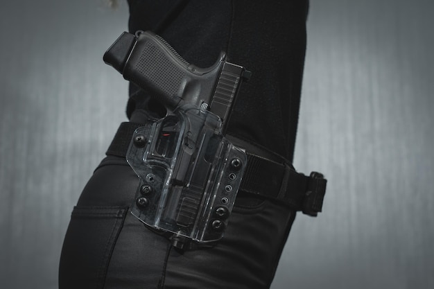 Photo a transparent plastic holster with a pistol on a girl's belt closeup photo high quality photo