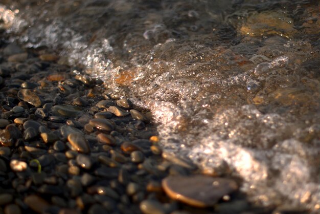 A transparent sea wave rolls over a pebble beach, recreation and travel, defocusing, bokeh.