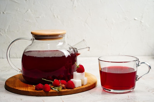 Transparent teapot and cup with red sweet tea with raspberries Detox berries antioxidant home health drink Copy space High quality photo