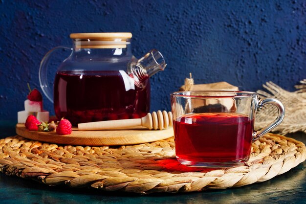 Transparent teapot and cup with red tea with raspberries and apples Detox antioxidant home health drink Copy space High quality photo