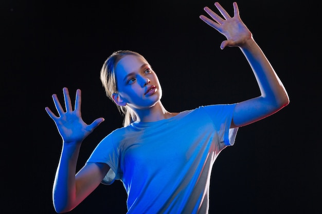 Transparent technology. Pretty blonde woman standing in front of the sensory screen while looking at her hands