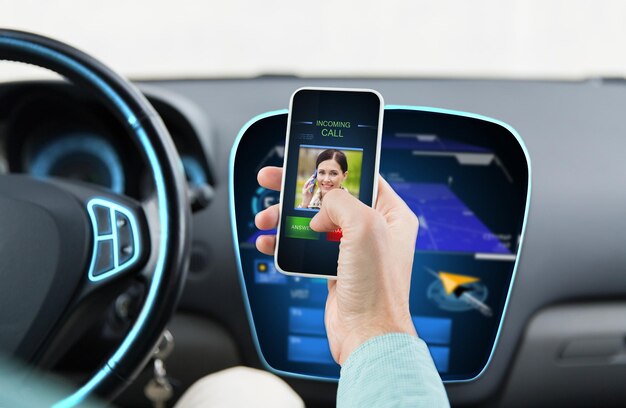 Photo transport, business trip, communication, technology and people concept - close up of male hand with incoming video call icon on smartphone screen in car