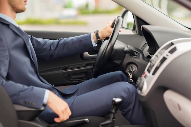 transport, business trip, destination and people concept - close up of young man in suit driving car