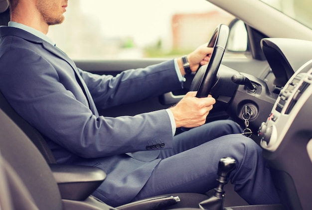 transport, business trip, destination and people concept - close up of young man in suit driving car