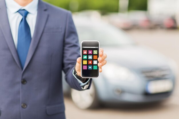 transport, business trip, multimedia, technology and people concept - close up of man showing menu icons smartphone screen on car parking