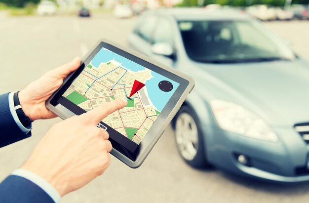 transport, business trip, navigation, technology and people concept - close up of male hands with gps navigator on tablet pc computer and car outdoors