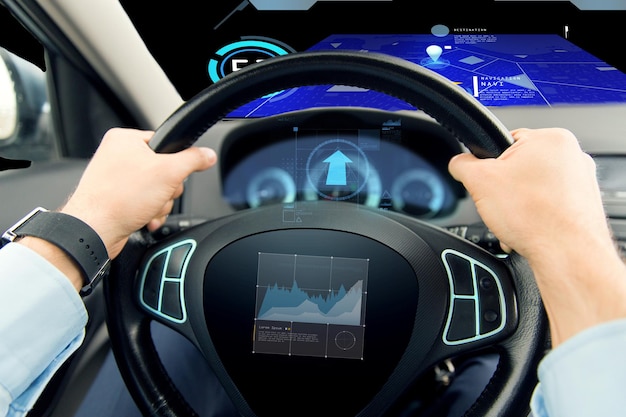 Photo transport, business trip, technology and people concept - close up of male hands holding car wheel and driving with graph on board computer screen