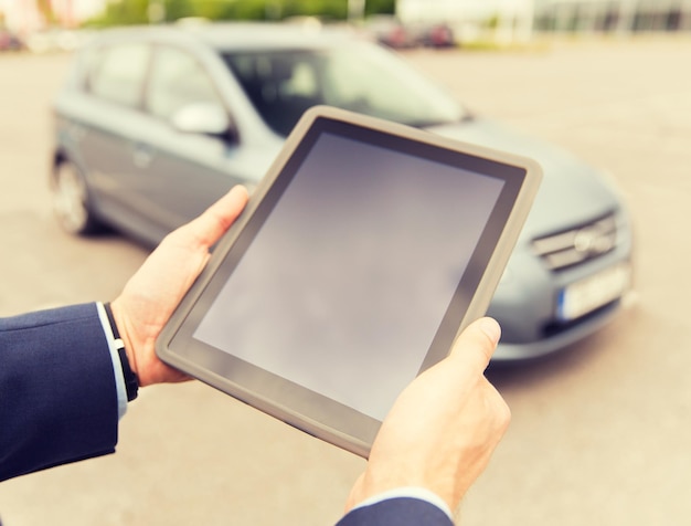 transport, business trip, technology and people concept - close up of young man with tablet pc computer on car parking