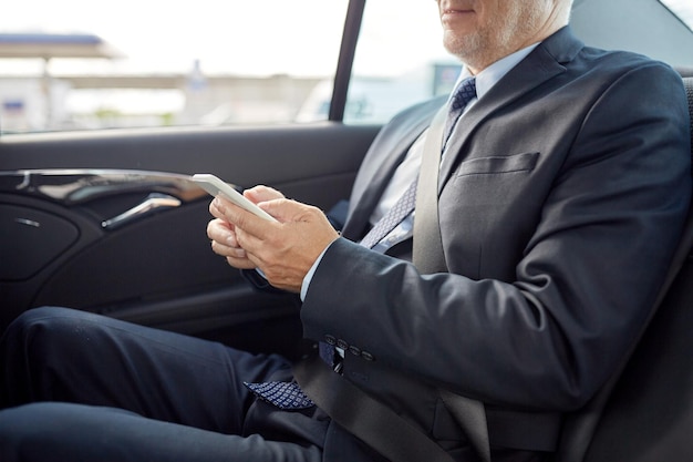 transport, business trip, technology and people concept - senior businessman texting on smartphone and driving on car back seat