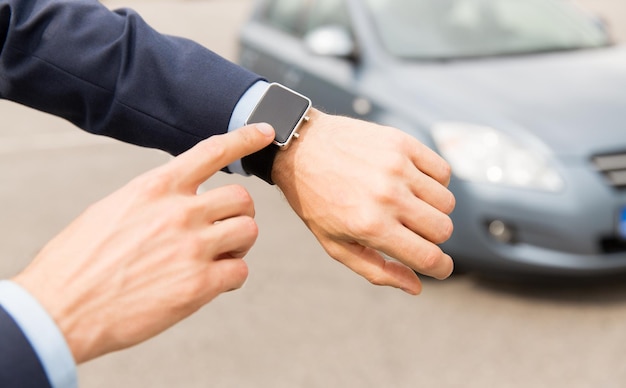 transport, business trip, technology, time and people concept - close up of male hands with wristwatch on car parking