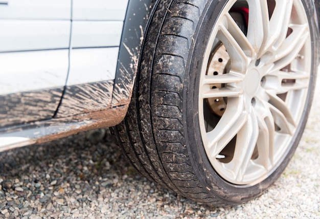 transport, driving and motor vehicle concept - close up of dirty car wheel on ground