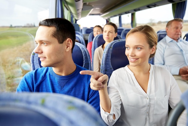 transport, tourism, road trip and people concept - happy couple with group of happy passengers or tourists in travel bus