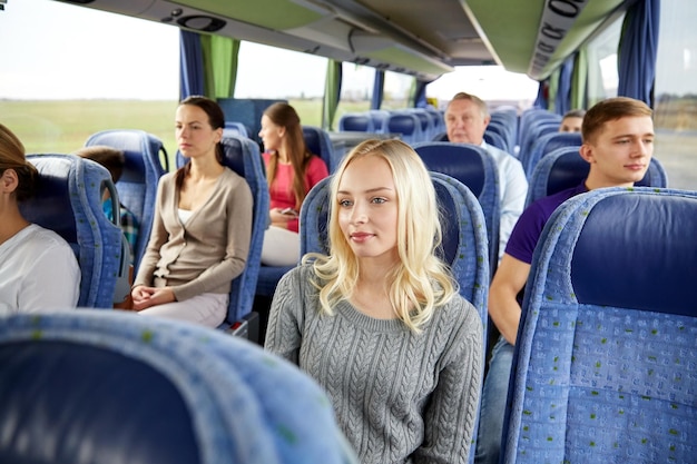 transport, tourism, road trip and people concept - young woman with group of passengers or tourists in travel bus