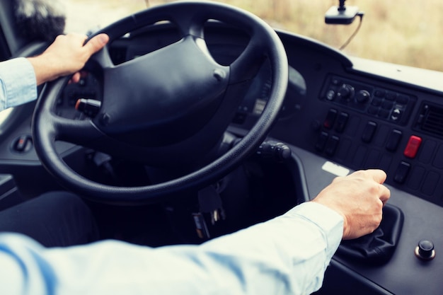 transport, transportation, tourism, road trip and people concept - close up of bus driver steering wheel and driving passenger bus