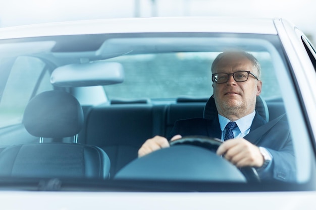 transport, zakenreis en mensenconcept - gelukkige senior zakenman rijdende auto