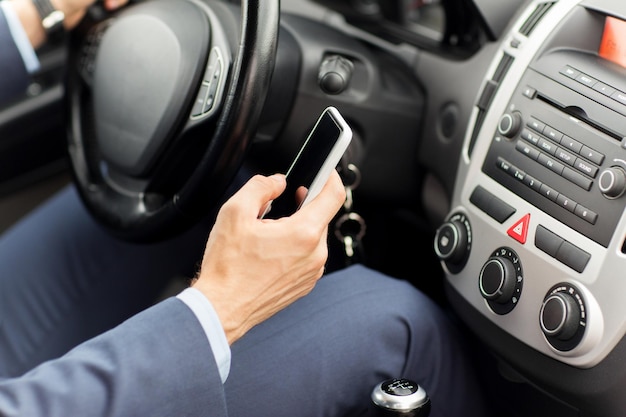 transport, zakenreis, technologie en mensenconcept - close-up van de hand van een jonge man met een smartphone die auto rijdt