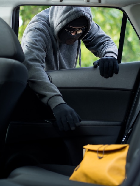 자동차에서 가방을 훔치는 교통 범죄 개념 도둑