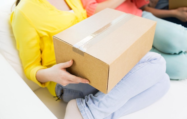 transportation, mail, delivery, shipping and people concept - close up of teenage girls with cardboard box at home