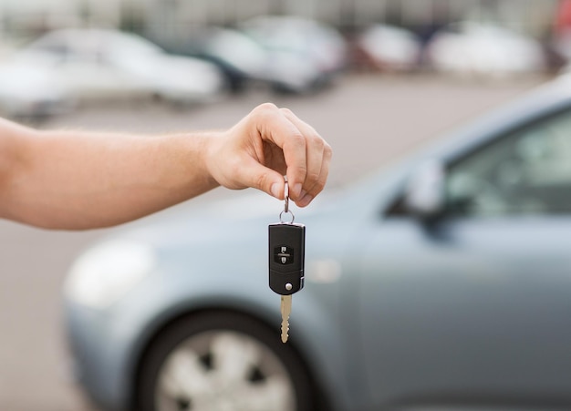 transportation and ownership concept - man with car key outside