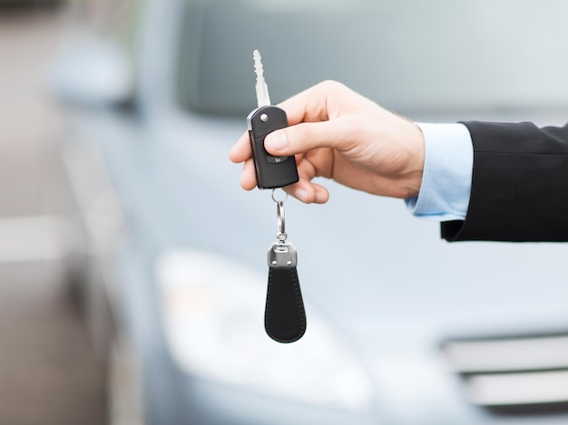 transportation and ownership concept - man with car key outside