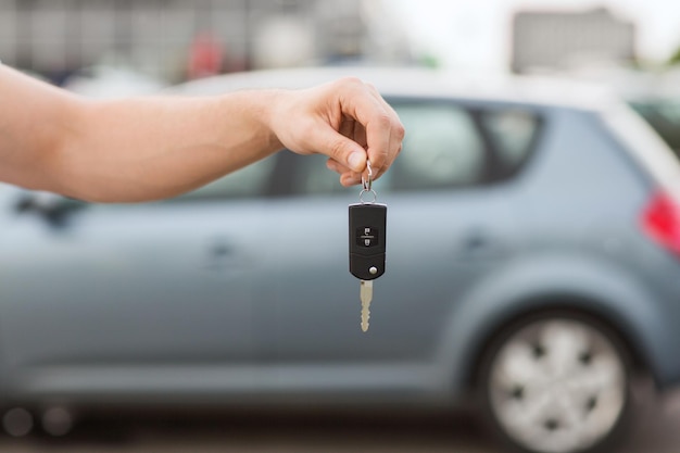 transportation and ownership concept - man with car key outside